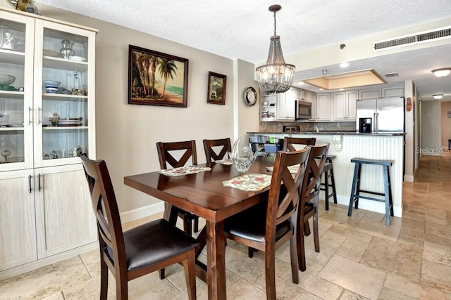 dining area with a textured ceiling and an inviting chandelier