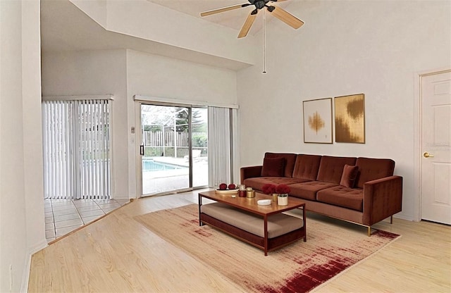 living room featuring ceiling fan, light hardwood / wood-style floors, and a high ceiling