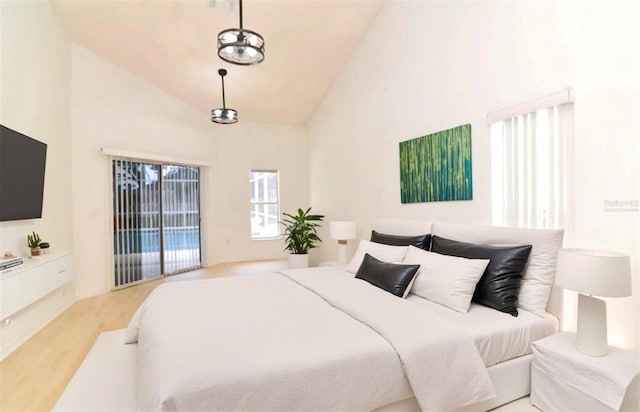 bedroom with an inviting chandelier, access to outside, high vaulted ceiling, and light hardwood / wood-style flooring