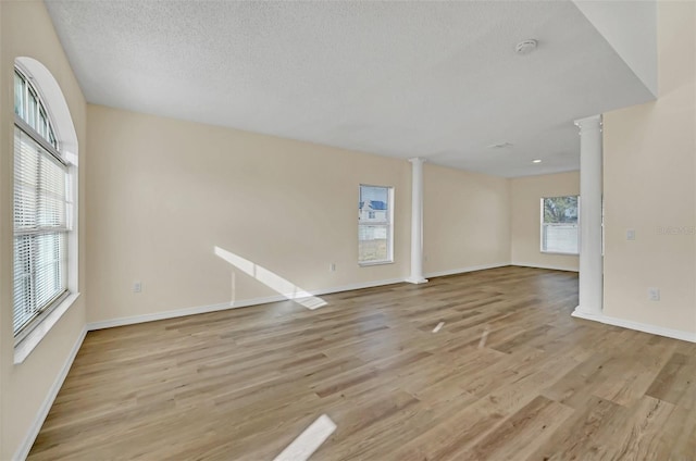 spare room with decorative columns and light hardwood / wood-style floors