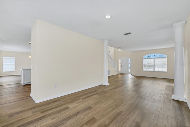 unfurnished living room with ornate columns and hardwood / wood-style flooring