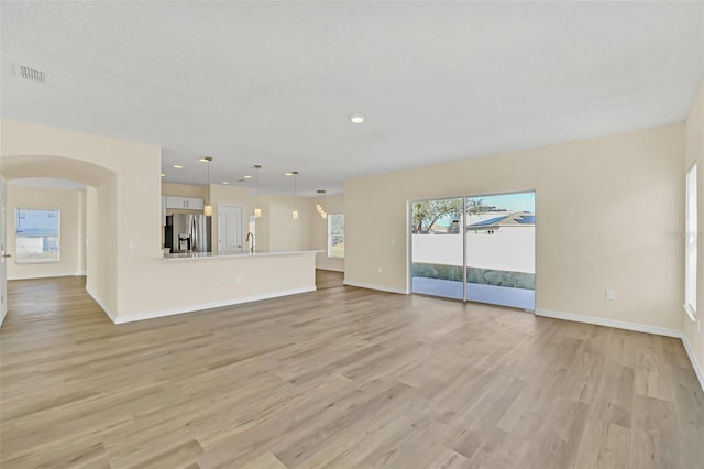 unfurnished living room with light hardwood / wood-style floors and sink