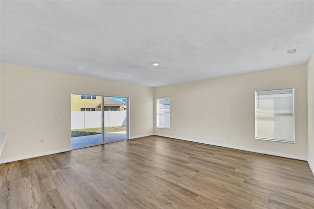 unfurnished room with light hardwood / wood-style floors and a textured ceiling