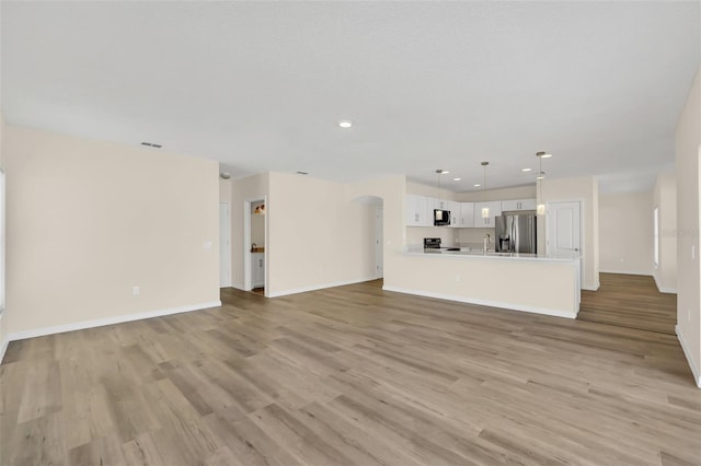 unfurnished living room with sink and light hardwood / wood-style flooring