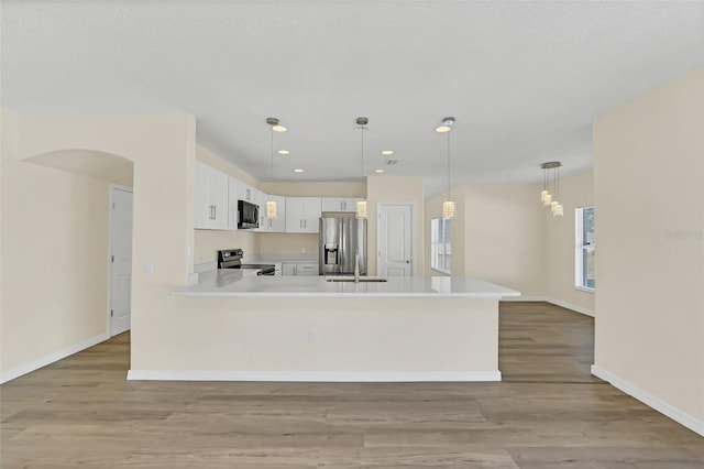 kitchen with white cabinetry, sink, stainless steel appliances, light hardwood / wood-style flooring, and decorative light fixtures