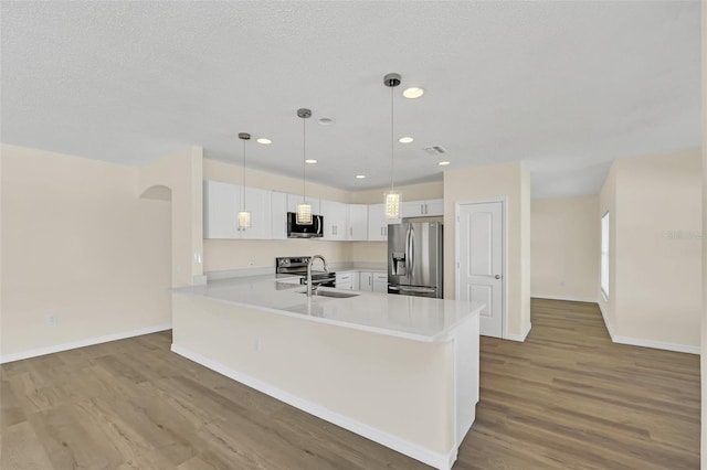 kitchen featuring white cabinets, sink, light wood-type flooring, decorative light fixtures, and stainless steel appliances