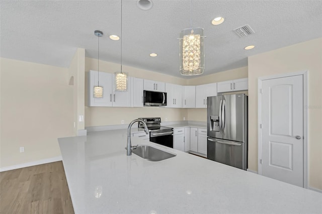 kitchen with pendant lighting, white cabinets, and stainless steel appliances