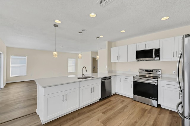 kitchen with kitchen peninsula, white cabinets, pendant lighting, and appliances with stainless steel finishes