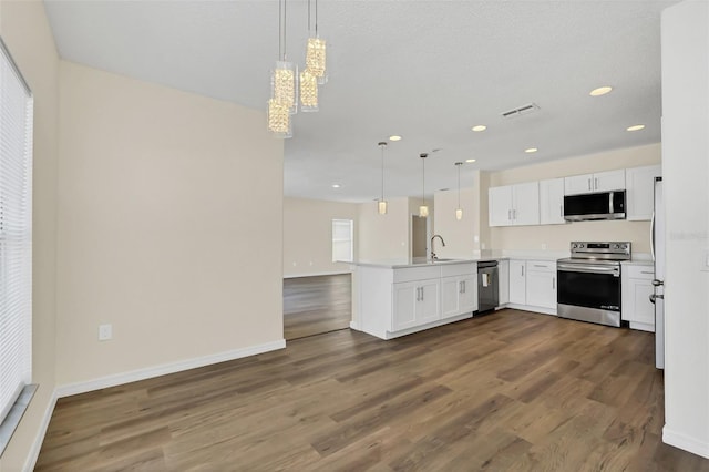 kitchen with kitchen peninsula, decorative light fixtures, stainless steel appliances, and white cabinets