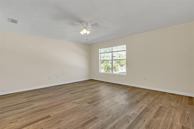 empty room featuring ceiling fan, wood-type flooring, and a textured ceiling