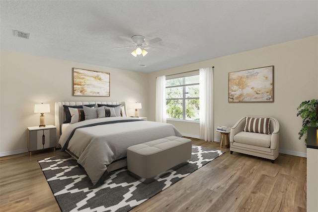 bedroom with ceiling fan, wood-type flooring, and a textured ceiling