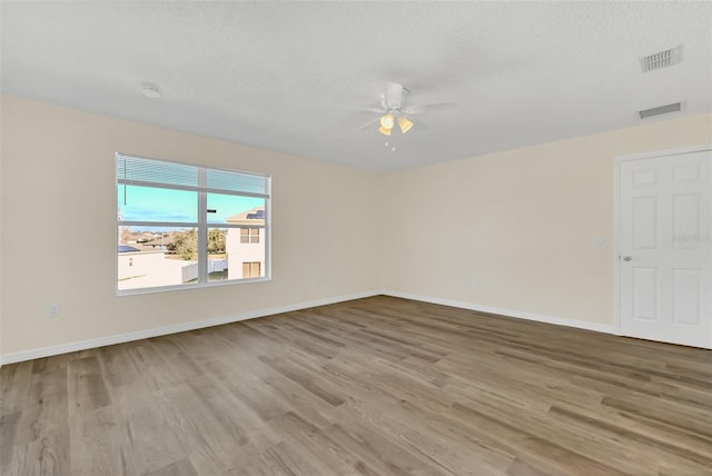 empty room with a textured ceiling, light hardwood / wood-style flooring, and ceiling fan