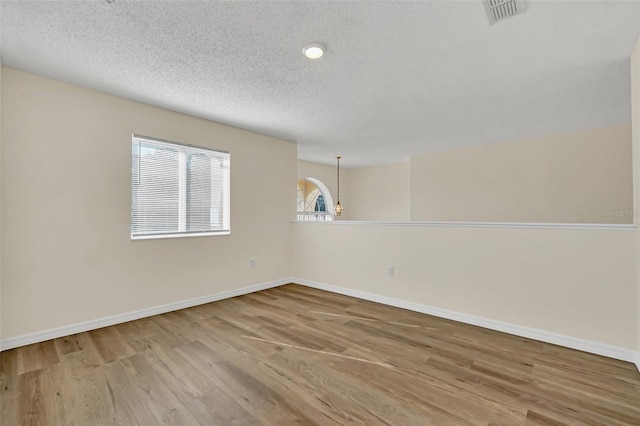 empty room with hardwood / wood-style floors and a textured ceiling