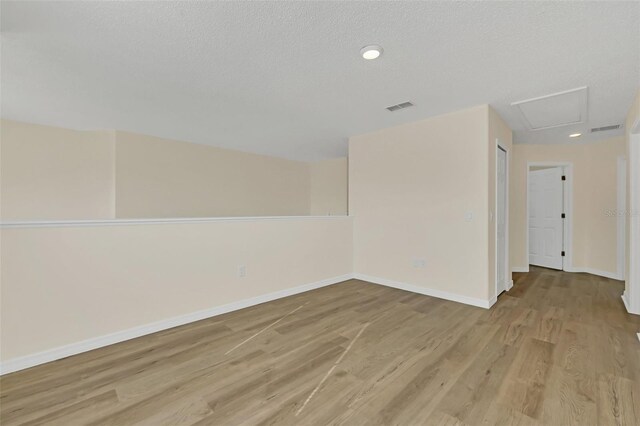 spare room with light hardwood / wood-style floors and a textured ceiling