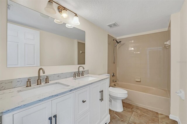 full bathroom with vanity, toilet, a textured ceiling, and tiled shower / bath