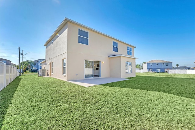 rear view of property featuring a yard, a patio, and central AC