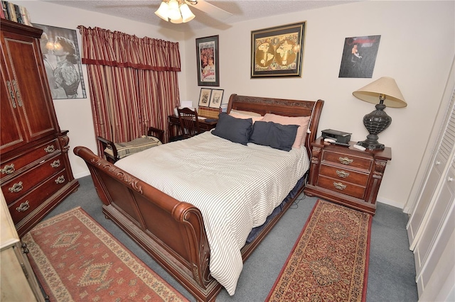 bedroom with ceiling fan, dark carpet, and a textured ceiling