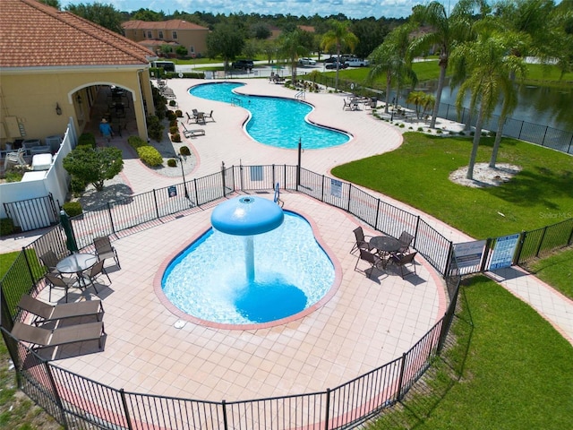 pool with a water view, fence, a lawn, and a patio