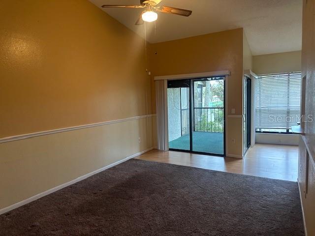 carpeted empty room featuring ceiling fan and vaulted ceiling