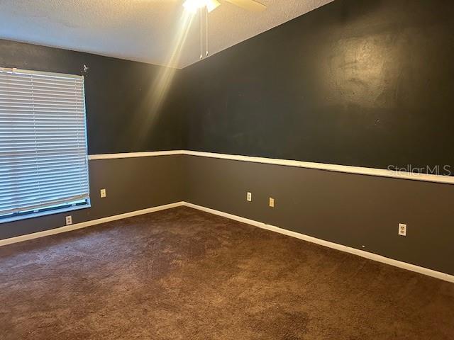 carpeted spare room with ceiling fan and a textured ceiling