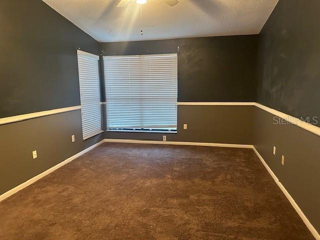 carpeted spare room featuring ceiling fan and a textured ceiling