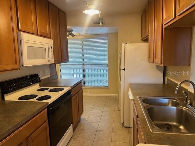 kitchen with white appliances, sink, and light tile patterned floors