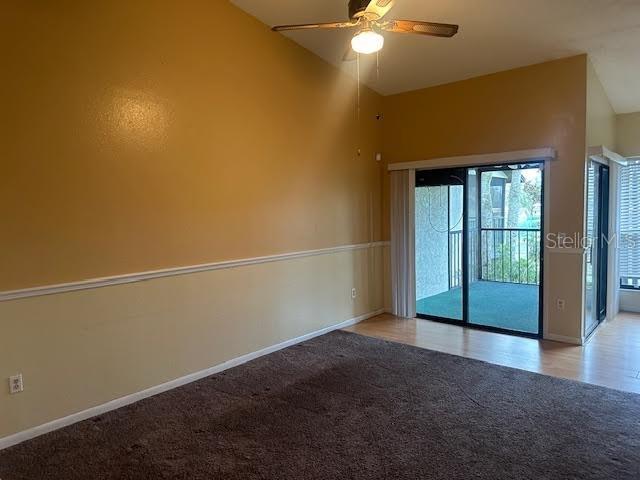 carpeted spare room featuring ceiling fan and lofted ceiling