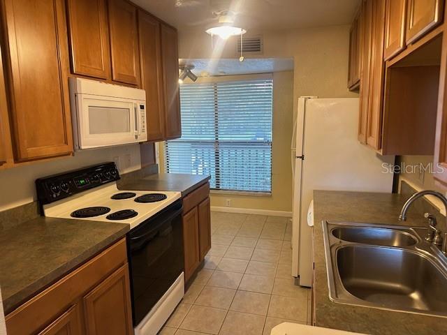 kitchen with light tile patterned flooring, white appliances, and sink