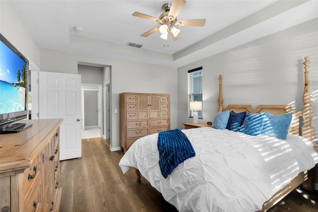 bedroom featuring a tray ceiling, ceiling fan, and dark hardwood / wood-style floors