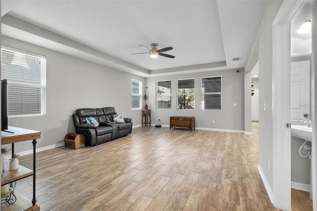 living room featuring a tray ceiling and ceiling fan