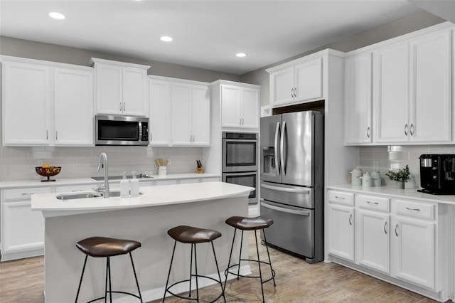 kitchen featuring white cabinetry, light hardwood / wood-style flooring, a kitchen island with sink, and appliances with stainless steel finishes