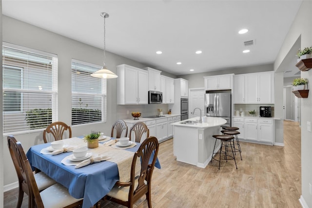 kitchen with pendant lighting, white cabinets, sink, an island with sink, and stainless steel appliances