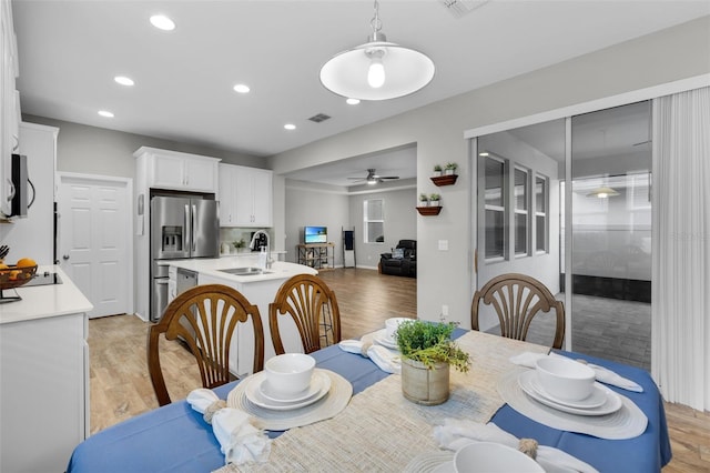 dining space featuring light hardwood / wood-style floors, ceiling fan, and sink