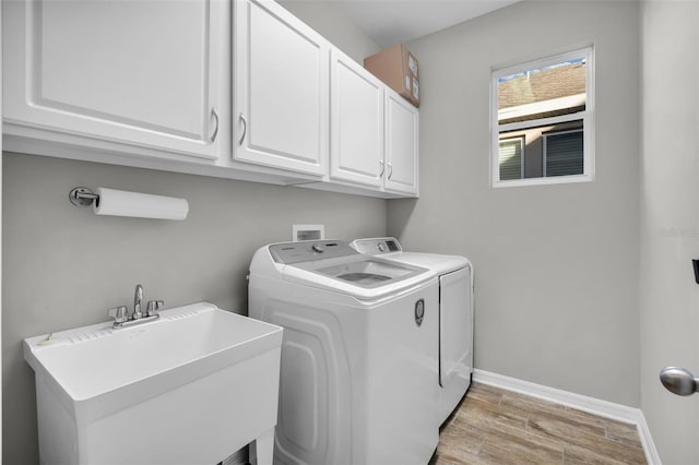 laundry room featuring washing machine and clothes dryer, sink, and cabinets