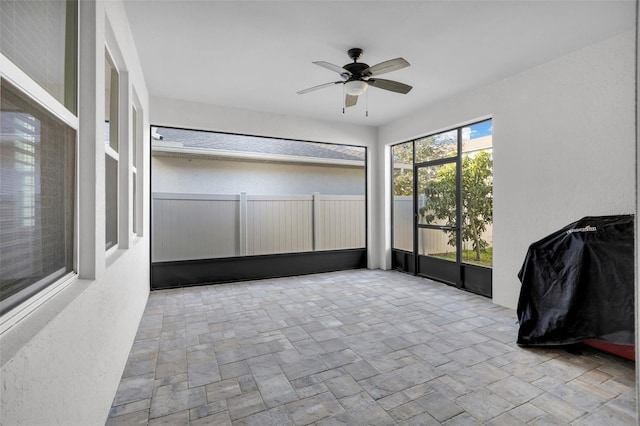 unfurnished sunroom featuring ceiling fan