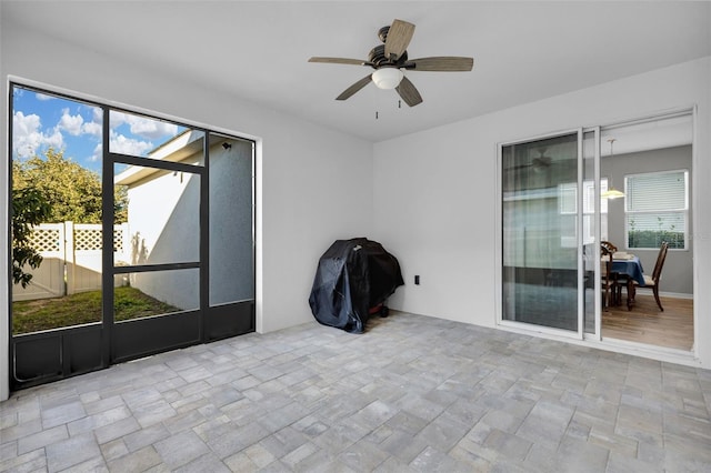 unfurnished sunroom featuring ceiling fan