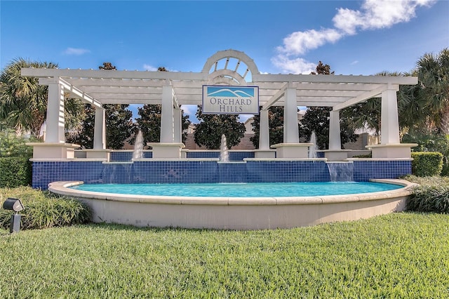 view of pool with a lawn and a pergola