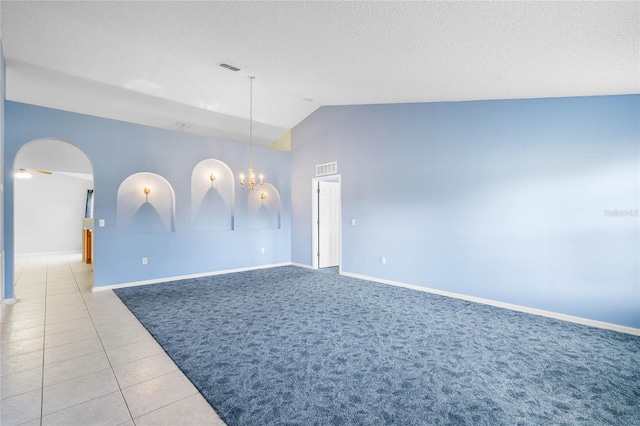 tiled spare room featuring a textured ceiling, ceiling fan with notable chandelier, and vaulted ceiling