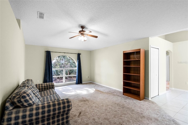 sitting room featuring a textured ceiling, light colored carpet, and ceiling fan