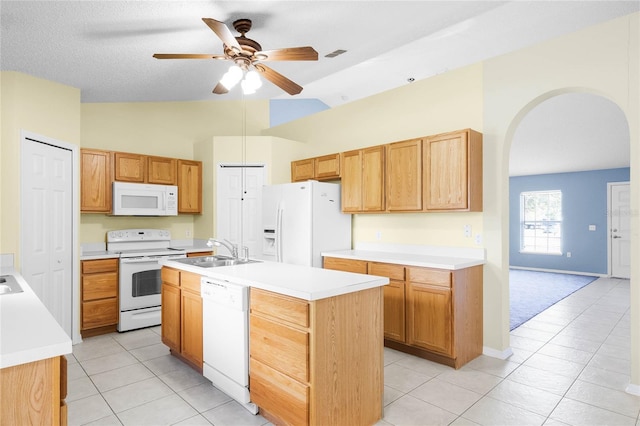 kitchen featuring ceiling fan, sink, vaulted ceiling, white appliances, and a kitchen island with sink