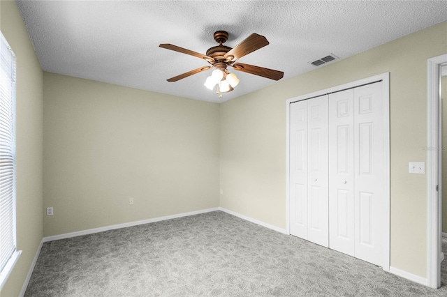 unfurnished bedroom featuring ceiling fan, carpet floors, a textured ceiling, and a closet