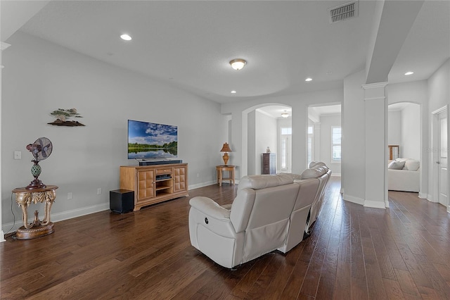 living room featuring decorative columns and dark wood-type flooring