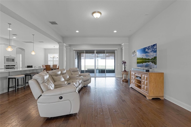 living room with a textured ceiling, ornate columns, and dark hardwood / wood-style floors