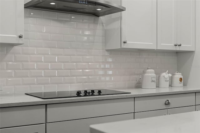 kitchen with backsplash, black electric stovetop, white cabinets, and range hood