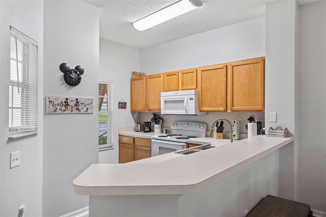 kitchen featuring a textured ceiling, sink, white appliances, and kitchen peninsula