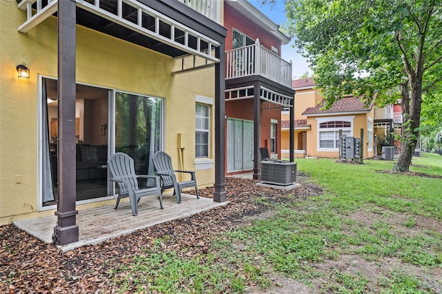 rear view of property with a balcony, cooling unit, a patio area, and a lawn