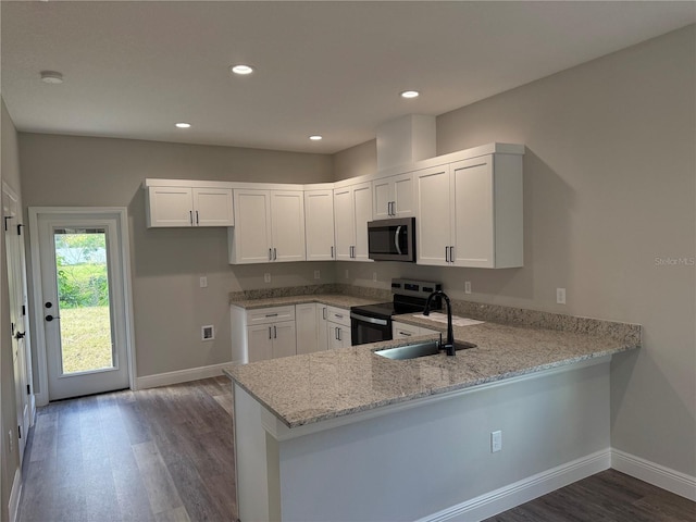 kitchen featuring kitchen peninsula, appliances with stainless steel finishes, white cabinetry, and light stone counters