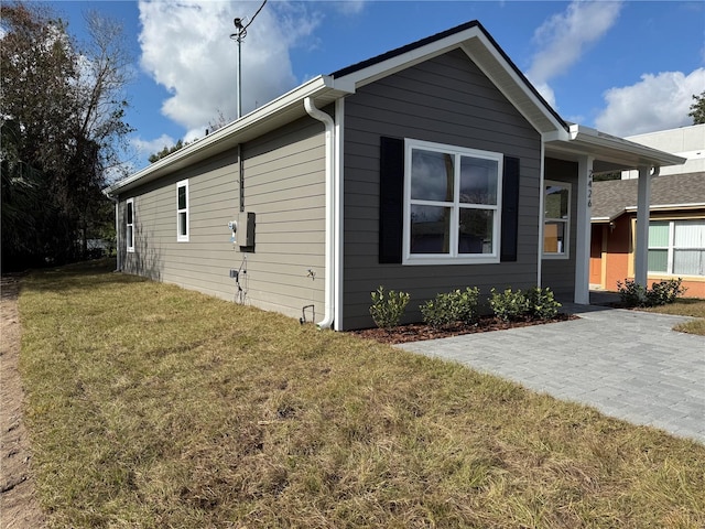 view of property exterior with a patio area and a lawn