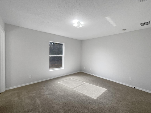 carpeted empty room featuring a textured ceiling