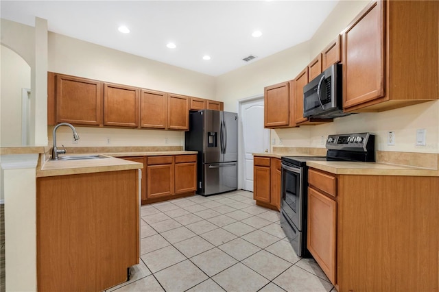 kitchen with kitchen peninsula, sink, light tile patterned floors, and appliances with stainless steel finishes